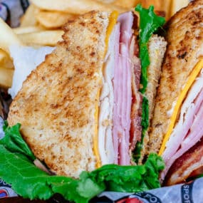 Club sandwich with Smoked turkey, sliced ham, crisp bacon with lettuce, tomato, cheddar cheese and mayo served on whole wheat bread with side of seasoned fries