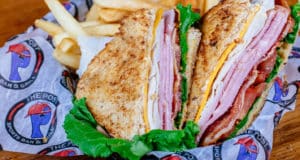 Club sandwich with Smoked turkey, sliced ham, crisp bacon with lettuce, tomato, cheddar cheese and mayo served on whole wheat bread with side of seasoned fries
