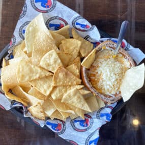Three cheese buffalo chicken dip with pita chips and tortilla chips on The Post Sports Bar & Grill sheet paper