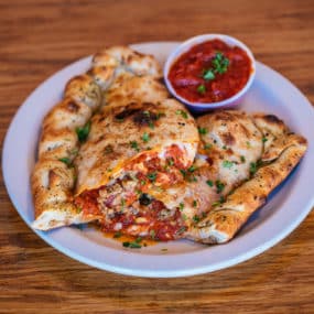 Calzone with homemade pizza dough stuffed with ricotta, mozzarella,  & two toppings of your choice