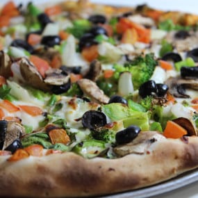 Veggie Pizza with Spinach, mushrooms, tomato, onion, green peppers, broccoli, and black olives on homemade dough