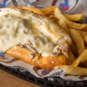 Beer Cheese Cheesesteak with Thinly sliced ribeye prepared with white American and smothered with homemade beer cheese. Served on a toasted hoagie with fries