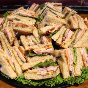Club Sandwich catering tray with Smoked turkey, sliced ham, bacon, lettuce, tomato, cheddar & mayo on whole wheat bread
