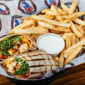 Buffalo chicken wrap with Breaded chicken tossed in hot sauce, lettuce, tomatoes, cheddar jack, & ranch inside a white tortilla with side of fries