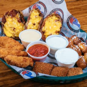 Delicious appetizer combo platter consisting of Potato skins, pretzel bites, toasted ravioli, and chicken fingers. Served w/Sour cream, ranch, beer cheese, & marinara
