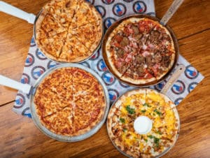4 pizzas on a table at The Post Sports Bar & Grill