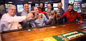 Members of The Post Leadership team The Post Sports Bar & Grill Maplewood cheersing with a beer